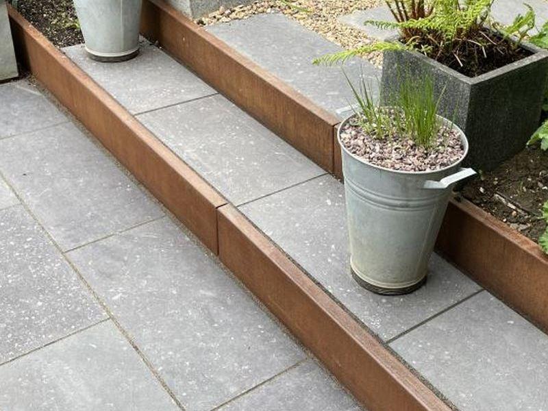 Structural backing of a corten steel retaining wall during soil backfilling.