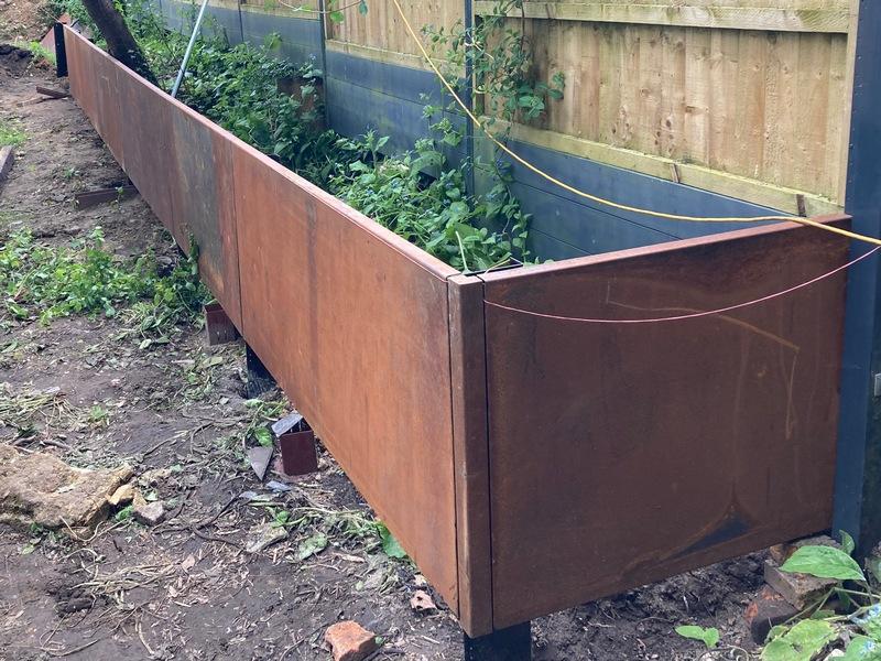 Multi-level steel retaining wall panels creating usable flat lawn space.