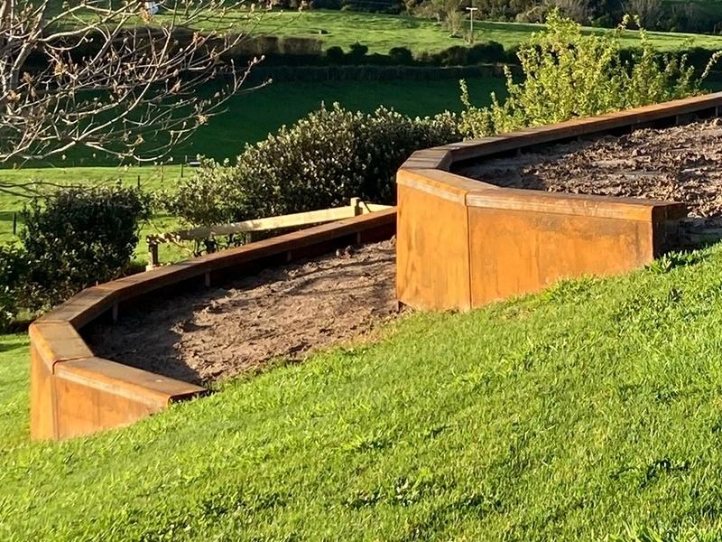 Leveling steel retaining wall panels in a narrow side-passage garden.