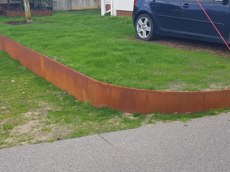 Raised vegetable garden beds built from steel retaining wall panels.